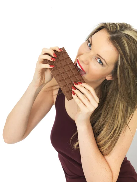 Mulher jovem segurando uma barra de chocolate de leite — Fotografia de Stock