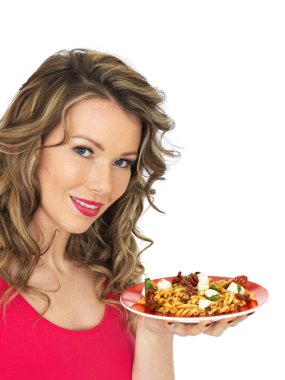 Genç kadın bir beyaz peynir yiyip Tommato makarna salatası