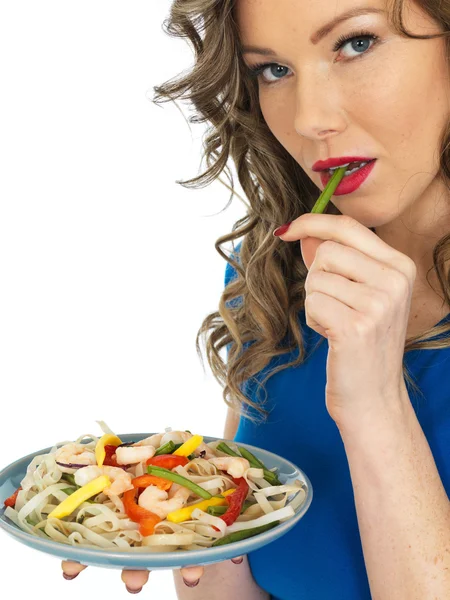 Jovem mulher comendo uma salada de camarão e macarrão — Fotografia de Stock