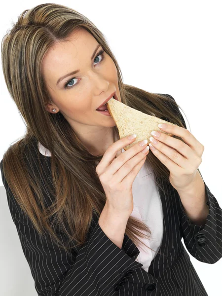 Jovem mulher de negócios comendo um sanduíche de pão marrom — Fotografia de Stock