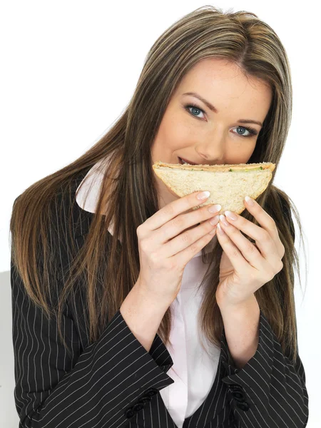 Jovem mulher de negócios comendo um sanduíche de pão marrom — Fotografia de Stock