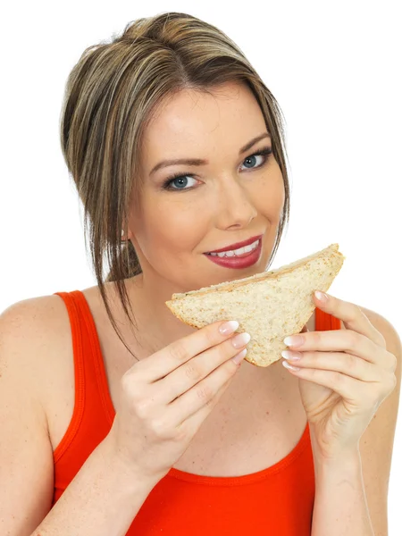 Mujer joven comiendo un sándwich de pan marrón salmón y pepino — Foto de Stock