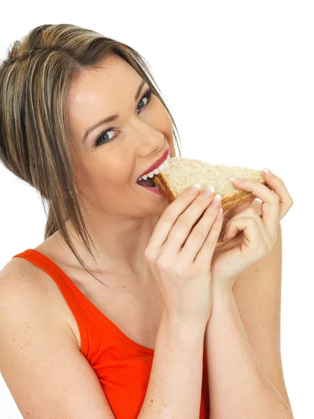 Mujer joven comiendo un sándwich de pan marrón salmón y pepino — Foto de Stock