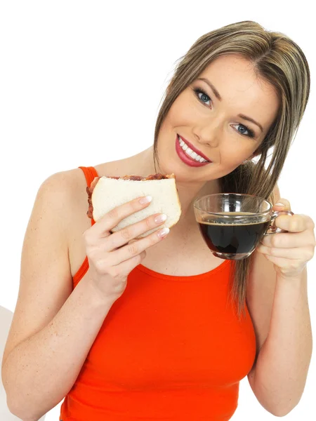 一杯黑咖啡和熏肉三明治的年轻女子 — 图库照片