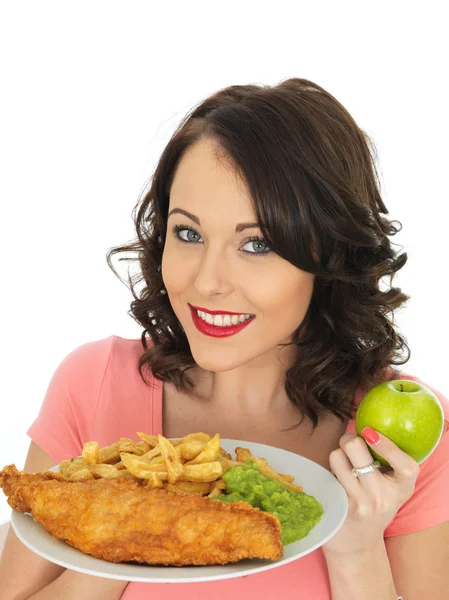 Ung kvinde spiser fisk og chips med grødet ærter - Stock-foto