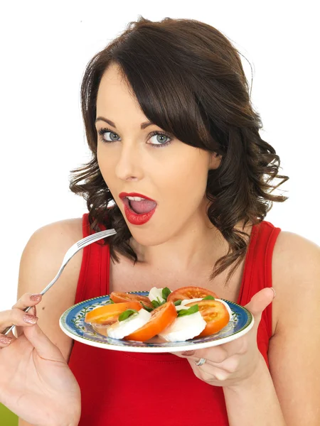 Mujer joven comiendo una ensalada de queso y tomate Mozzarella —  Fotos de Stock