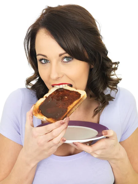 Jeune femme tenant pain grillé propagation avec Marmite — Photo