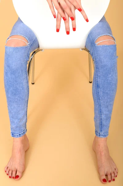 Primo piano di mani e piedi di un modello seduto in jeans strappati — Foto Stock