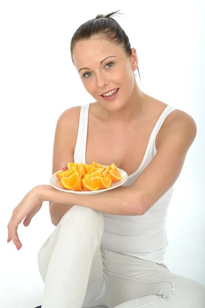 Atractiva mujer joven sosteniendo una placa de naranjas maduras frescas cortadas —  Fotos de Stock