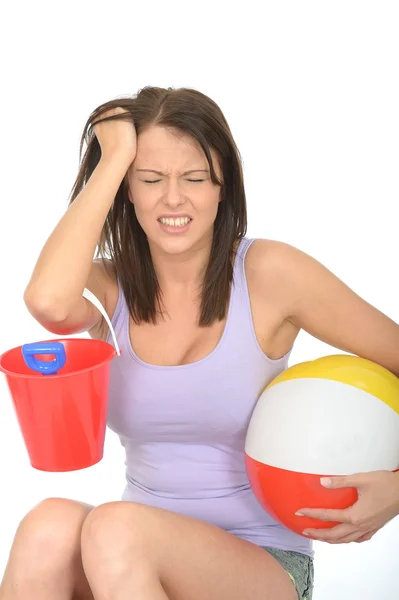 Mujer joven frustrada en vacaciones sosteniendo un cubo y una pelota de playa — Foto de Stock