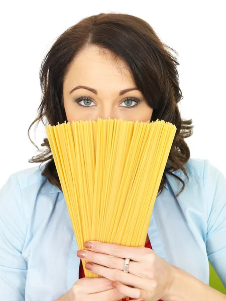 Attraktive junge Frau in ihren Zwanzigern mit einer Handvoll getrockneter Spaghetti — Stockfoto