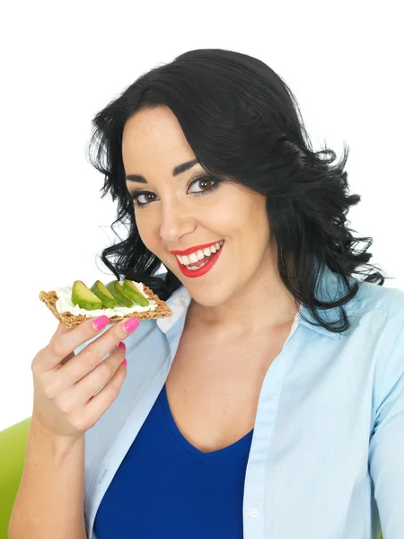 Junge Frau isst Cracker mit Quark und Avocado — Stockfoto