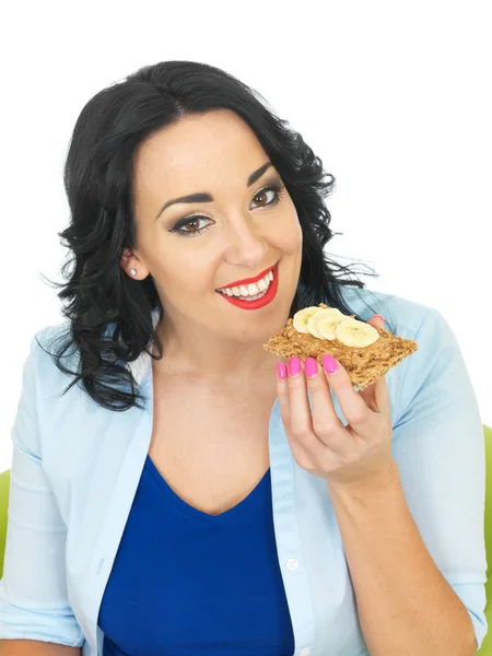 Mujer sana comiendo una galleta con mantequilla de maní y plátano en rodajas —  Fotos de Stock