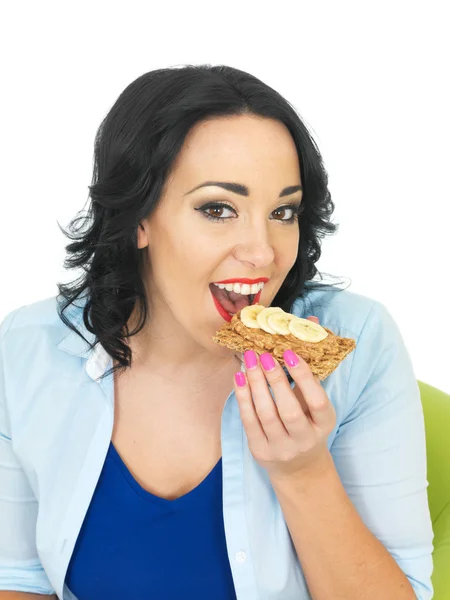 Gesunde Frau isst Cracker mit Erdnussbutter und geschnittener Banane — Stockfoto