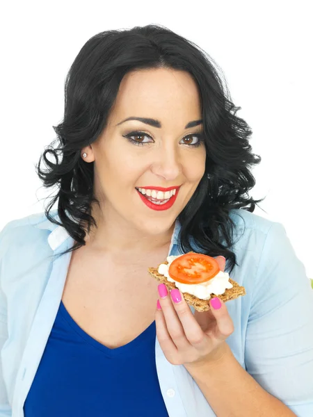 Молодая женщина ест крекер с творогом и помидорами — стоковое фото