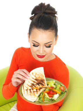 Güzel genç İspanyol kadın olarak bir parlak kırmızı Jumper bir tabak Meksika tavuk Quesadula ve salata ile