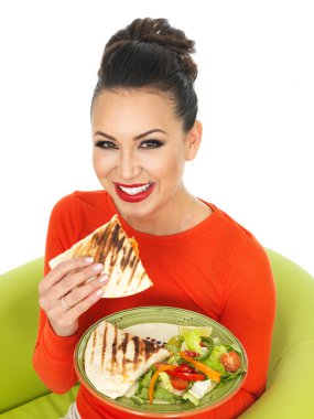 Güzel genç İspanyol kadın olarak bir parlak kırmızı Jumper bir tabak Meksika tavuk Quesadula ve salata ile