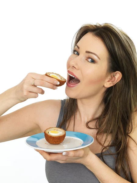 Jovem mulher atraente comendo um ovo escocês saboroso — Fotografia de Stock
