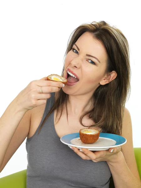 Jovem mulher atraente comendo um ovo escocês saboroso — Fotografia de Stock