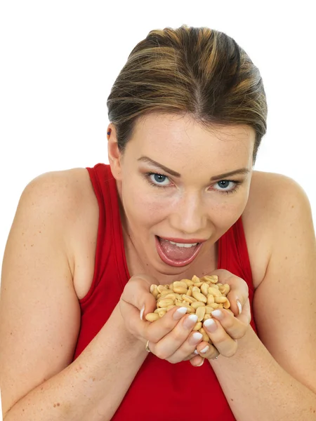 Attraente giovane donna che tiene una manciata di arachidi arrosto salate — Foto Stock