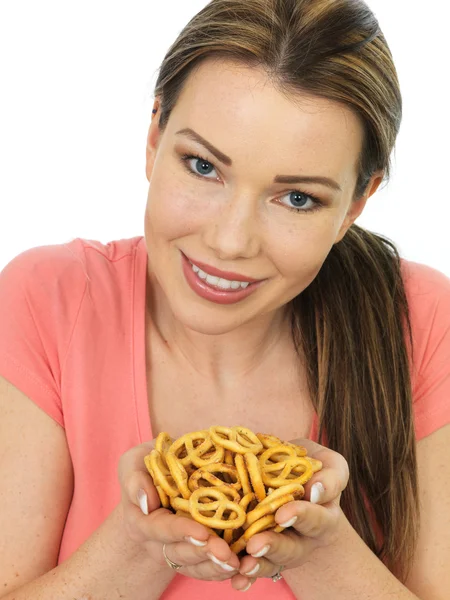 Attraente giovane donna che tiene una manciata di pretzel salati — Foto Stock