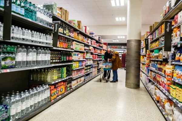 London UK, November 19 2025, Senior Couple In Supermarket With Shopping Trolley Browsing Products