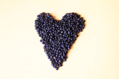 Sarı zemin üzerinde kalp şeklinde kahve çekirdekleri ve fotokopi alanı. Sevgililer Günü, aşk konsepti.