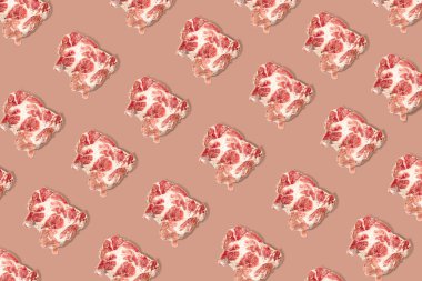 Pembe arka planda çiğ domuz eti dilimleri ve biftekli kusursuz yemek kalıbı..