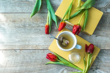 Yeşil bitki çayı, kırmızı lale buketi, çiçekler ve kitaplar. Kadınların anneleri günü. Fotokopi alanı ile bahar çiçeği konsepti..