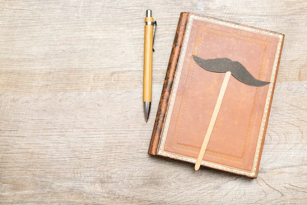 Happy fathers day holiday concept, notebook with pen and mustache on a rustic wooden background with copy space, Male man present.