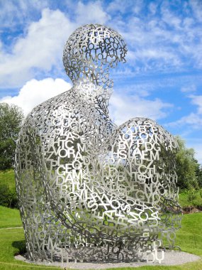 Modern mimari, sanat demir harfleri, güneşli yaz günü açık hava parkında çimlerin üzerinde dizlerini tutan insanın heykeli, bilgi kavramı Ukrayna, Kiev, 15 Haziran 2012.