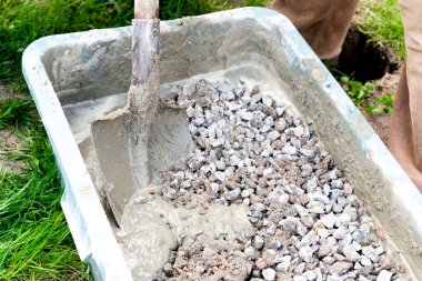 İşçi karıştırıyor, karıştırıyor, çimento karıştırıyor, beton moloz molozuyla büyük kâsede kürek, su deposu, yalak, kova. İnşaat süreci, yenileme, temel atma hazırlıkları.