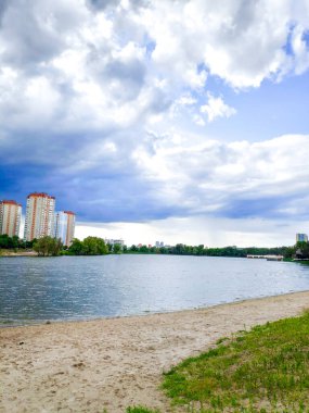 Kentsel göleti olan güzel şehir manzarası, yerleşim bölgesi yakınlarında göl fırtınadan, yağmurdan, gök gürültüsünden önce parlak mavi gökyüzüne karşı yeni binalar..