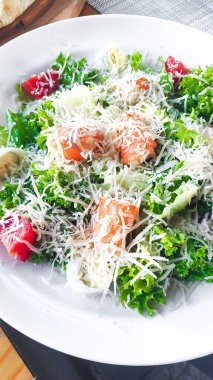 Somon ve parmesanlı taze sezar salatası. Restorandaki ahşap masaya yakın. organik vejetaryen yemekleri.