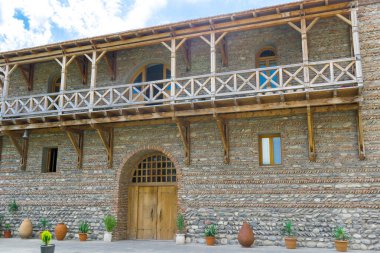 Yazın güneşli bir günde mavi gökyüzüne karşı ahşap büyük kapı, balkon, eski harap tuğla kale kilit duvarı.