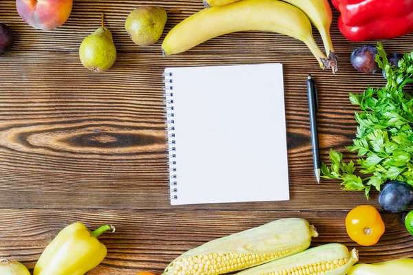 新鮮な果物や野菜と夕食のためのダイエットフィットネス菜食主義者の食べ物 ノートブックと木製の背景のノートのペンで痩身計画トップビューのフレームフラットフラットレイアウト — ストック写真