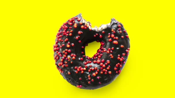 Detener el movimiento creativo concepto de animación de vídeo de desaparecer o morder comer deliciosa rosquilla dulce negro muerde sobre fondo amarillo.Timelapse. Vista superior plano lay concepto de alimentos — Vídeo de stock