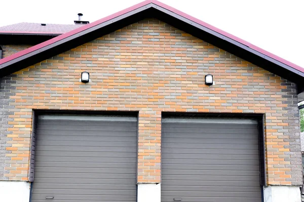 Nova garagem de estacionamento moderno em casa de tijolo de luxo residencial para construção de dois carros com persianas em portões — Fotografia de Stock