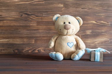 Tahta masanın üzerinde hediye kutusu ve fotokopi alanı olan küçük oyuncak ayı. Bebek partisi, aksesuarlar, eşyalar, erkek çocuk için hediye ilk yıl doğum günü, yeni doğan parti geçmişi.