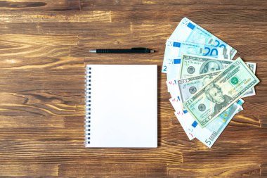 Bir sürü euro, Amerikan doları banknotlar, tahta masadaki notlar için kalemli defter. para nakit finans bütçe iş konsepti, üst görünüm, kopyalama alanı.