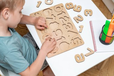 Çocuk ahşap mozaik tahtasıyla oynuyor. Çocuk numaraları öğreniyor, matematiği sayıyor. Çocuk mantığı, erken duyusal eğitim, iyi motor becerileri gelişimi.