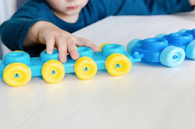 Mozaik yapımcısıyla oynayan küçük bir çocuk. Bebek yapım figürleri. Çocuk mantığı, iyi motor beceriler.