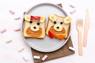 Komik sevimli ayı, köpek suratlı tost ekmeği. Çocuklar tatlı tatlı tatlı tatlı kahvaltı sağlıklı öğle yemeği sanatı fıstık ezmesi, muz, elma tabakta, kapat, üst manzara