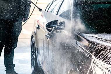 Yüksek basınçlı su jeti olan, otomatik oto yıkamada ekipman pompalı, köpüklü kimyasal deterjan kaplı bir araç.