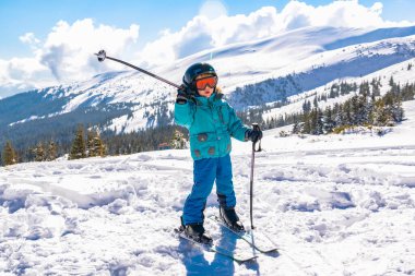 Aktif, kasklı, gözlüklü, yakışıklı çocuk. Dağlarda kayak yapmayı öğreniyor. Kış tatilinde.