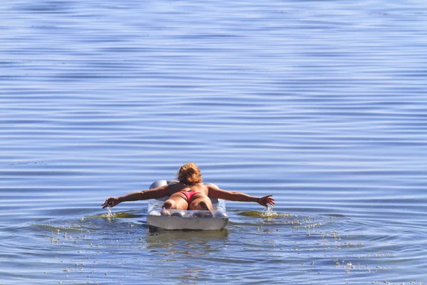 Bonito esportes menina flutua em um colchão inflável — Fotografia de Stock