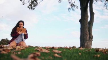 Yalnız bir ağacın altında kitabı olan bir kız