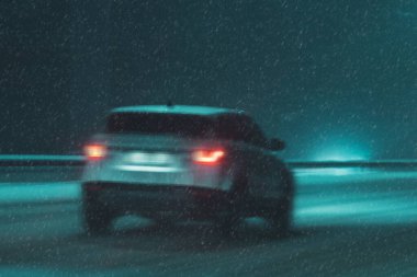 Karlı bir yolda gece araba sürüyor.