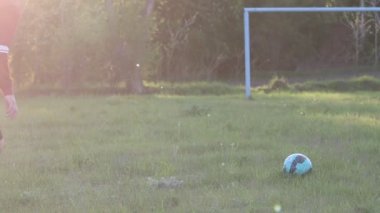 Çocuklar yeşil sahada futbol oynuyorlar.