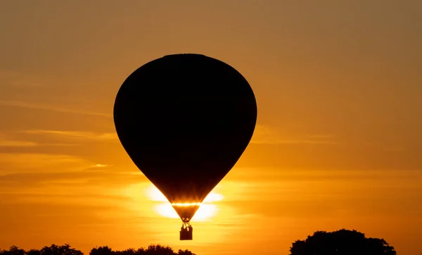 Hete lucht ballon met reizigers vliegen bij zonsondergang — Stockfoto